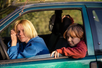 Tired mother driving a car and a young boy son are sitting. Halt on the road, exhaustion, frustration concept.