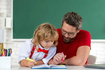 Fototapete - Teacher helping child student pupil from elementary school in classroom. Pupil kid student and teacher tutor in classroom at school lesson.