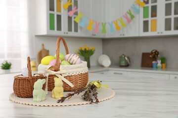 Sticker - Wicker baskets with Easter eggs and willow twigs at white marble table in kitchen, space for text