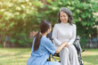 © NanSan - Young asian care helper with asia elderly woman on wheelchair relax together park outdoors to help and encourage and rest your mind with green nature.