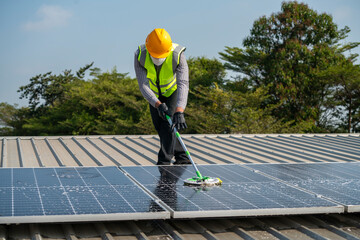 Wall Mural - Maintenance technician using cleaning mop and to clean the solar panels that are dirty with dust to improve the efficiency of solar energy storage.