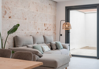 Wall Mural - Light grey living room sofa with pillows in front of a natural stone wall	
