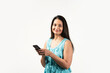 Portrait of a smiling Mid aged Indian woman holding smartphone over white background