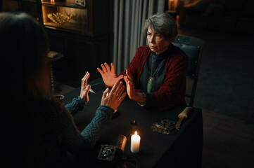 Wall Mural - Fortune teller sorceress and woman doing spiritual ritual over candle flame