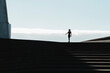 © Cavan Images - Silhouette of woman walking on stairs with blue sky in background