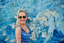 Delighted Woman In Sunglasses Standing Against Shabby Colourful Wall