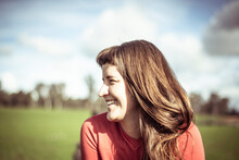 Girl With Fringe Laughs In Sunlight Out On Green Farm Land In Spring