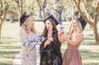 © Cavan Images - Three caucasian women in graduation caps laughing and popping confetti