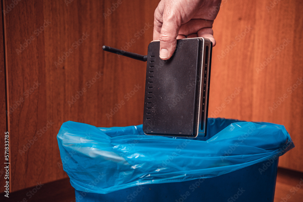 A man throws a WiFi router in the trash. Man&rsquo;s hand with a WiFi 