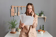 © sementsova321 - Portrait of smiling happy brown haired businesswoman wearing beige suit standing near table on kitchen at home, holding documents and talking on smart phone with business partner.