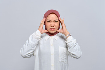 Wall Mural - Young Asian Muslim woman pressing finger to temple, having headache, feeling depressed after work isolated over white background