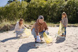 © Julija - Family volunteers picking up trash on the beach. Environment protection volunteer and waste pollution concept.