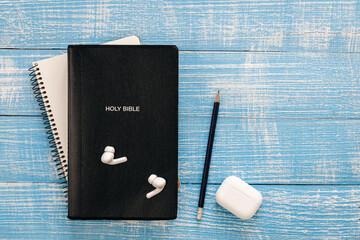 Wall Mural - Bible, notebook and earphones on a blue wooden background, flat lay, copy space.