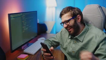 young man programmer working at night and checking message in smartphone, joy by win in lottery