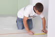 © New Africa - Man using measuring tape during installation of laminate flooring in room