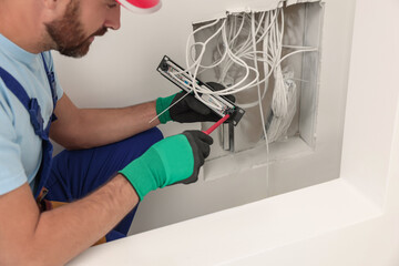 electrician with screwdriver fixing patch panel indoors, closeup