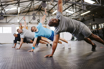 Wall Mural - People, fitness and side plank in class with personal trainer for workout, stretching exercise or training. Diverse group in warm up stretch session with coach for cardio wellness or balance on floor