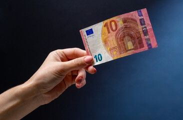 Hand holding ten euro banknote after money exchange. European currency in cash as symbol of success and wealth