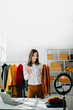© Nuttapong punna - Fashion blogger concept, Young Asian women selling clothes on video streaming.Startup small business SME, using smartphone or tablet taking receive and checking.