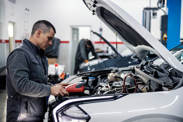 Wall Mural - Profile of a mechanic's shop employee doing accumulator diagnostics with special device.