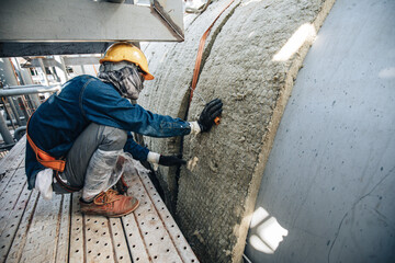 Canvas Print - Male workers lay the sheets on the insulation tank.