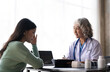 © Natee Meepian - Woman senior doctor is Reading Medical History of Female Patient and Speaking with Her During Consultation in a Health Clinic. Physician in Lab Coat Sitting Behind a Laptop in Hospital Office
