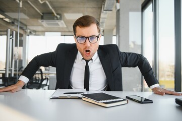 Wall Mural - Angry businessman sitting at the table and screaming.