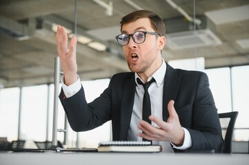 Wall Mural - Angry businessman sitting at the table and screaming.