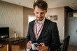 © Miljan Živković - one man adult caucasian businessman wear suit in hotel room while taking a brake or prepare for work hold cup of coffee and smartphone sending sms messages copy space