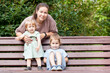 © Kekyalyaynen - Caucasian woman with two daughters on a park bench, family with mother and kids
