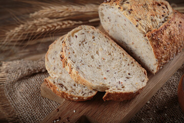 Wall Mural - Sliced fresh baked whole grain bread with oats, flax seeds and sesame seeds on rustic wooden board. Bakery products