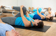 © JackF - Acitve male and female of different ages lying on mats during Pilates stretching training in fitness studio