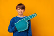 Cute young smiling boy wearing blue foam fan finger glove points aside.