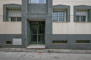 Wall Mural - Portal of a building with green stone, green metal door and cream-colored plaster