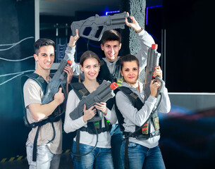 Canvas Print - Cheery people posing with laser guns having fun on dark lasertag arena