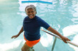 © Wavebreak Media - Portrait of african american senior woman smiling while standing on the stairs of swimming pool