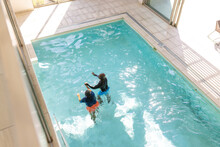Aerial View Of African American Senior Couple Swimming Together In The Swimming Pool