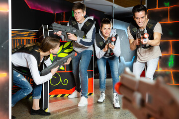 Canvas Print - Modern young people with laser pistols playing laser tag on dark labyrinth..