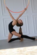 little gymnast in a black suit doing stretching with hoop