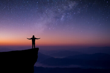 Wall Mural - Silhouette of young traveler and backpacker watched the star and milky way alone on top of the mountain. He enjoyed traveling and was successful when he reached the summit.