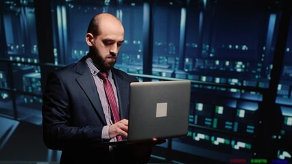 Poster - it manager technical support operator holding laptop in data center, working on computer mainframe w