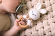 © New Africa - Cute newborn baby with pacifier and toy bunny on beige crocheted plaid, top view