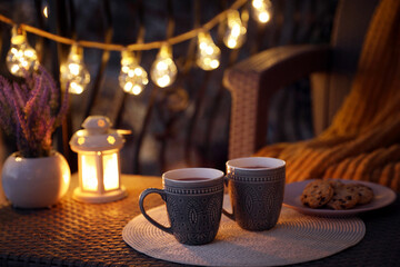 Sticker - Cups with tasty cocoa on rattan table at balcony in evening