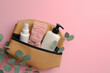 Preparation for spa. Compact toiletry bag with different cosmetic products and eucalyptus on pink background, flat lay. Space for text