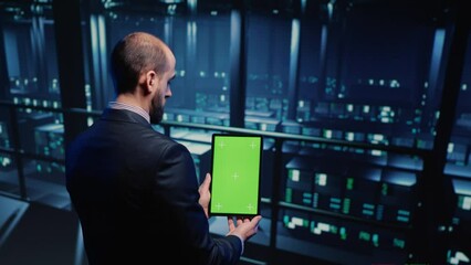 Poster - data center technician holding tablet with green screen in server room, looking at isolated chroma k