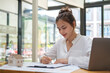 © wattana - Portrait of businesswoman sitting at office desk and checking documents.