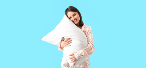 Wall Mural - Beautiful young woman hugging pillow on blue background