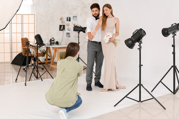 Poster - Female photographer taking picture of couple in studio