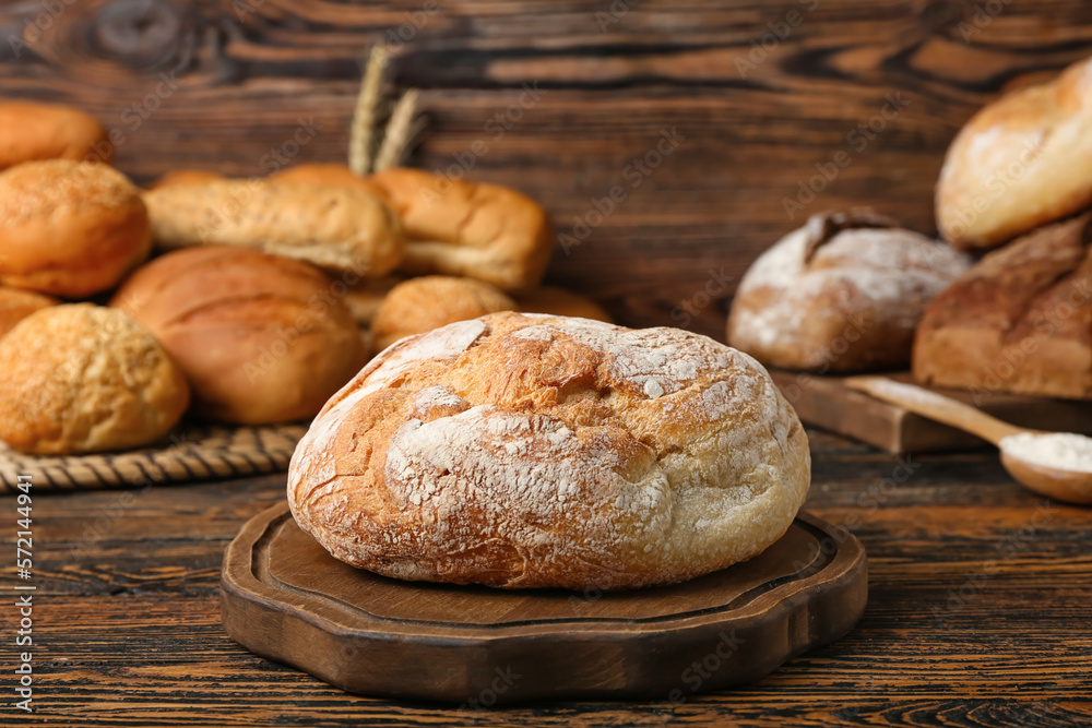 Cutting board with loaf of fresh bread on wooden table