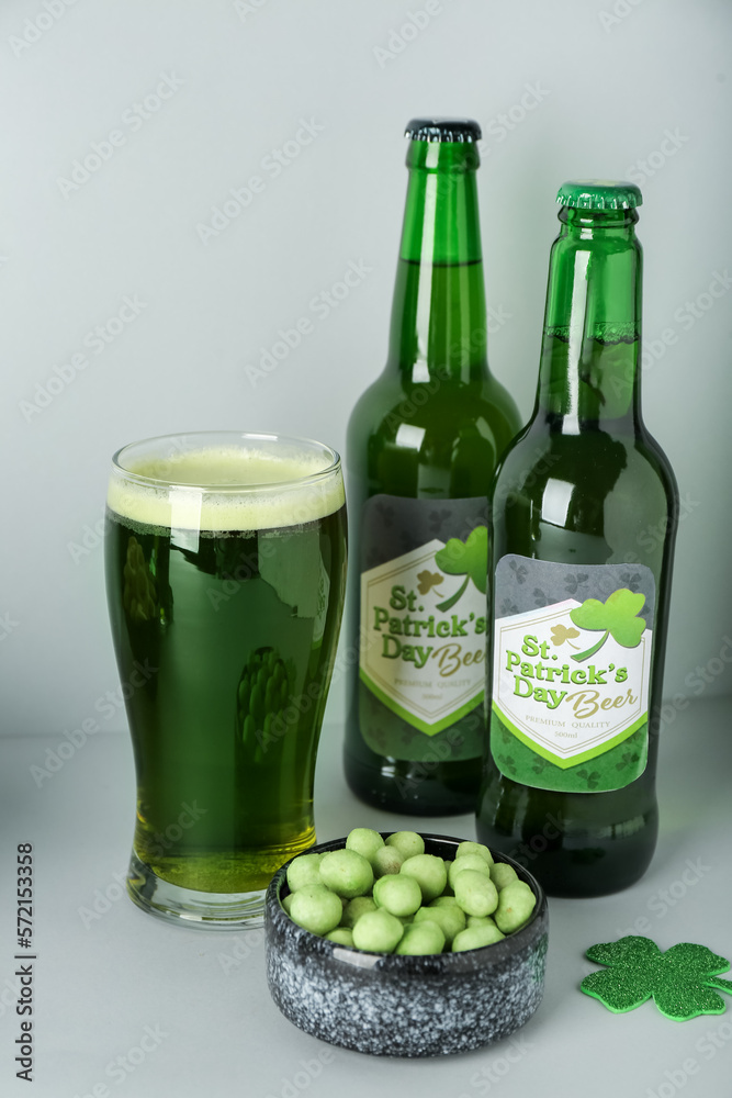 Glass with bottles of beer and snack on grey background. St. Patrick's Day celebration